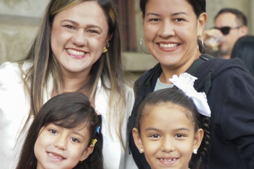 Dos mamás y dos niñas sonríen juntas en el Festival de Familias.