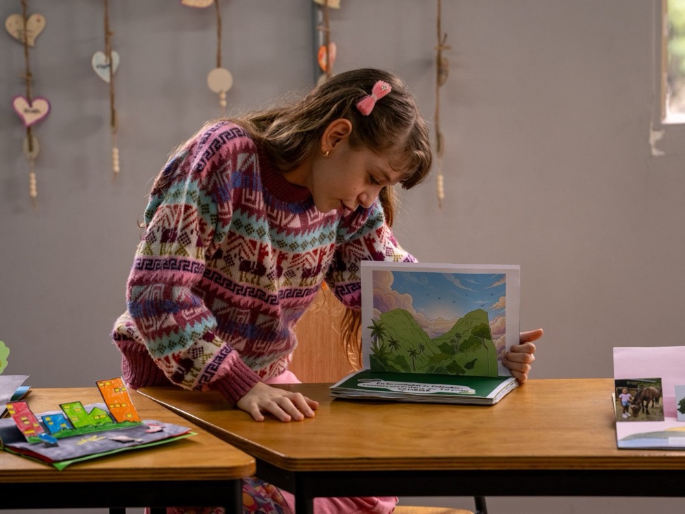 Una niña mira con atención el libro desplegable que construyó.
