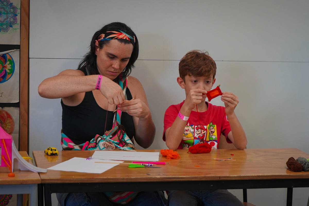 Una mamá y su hijo tejen juntos en un taller de sede.