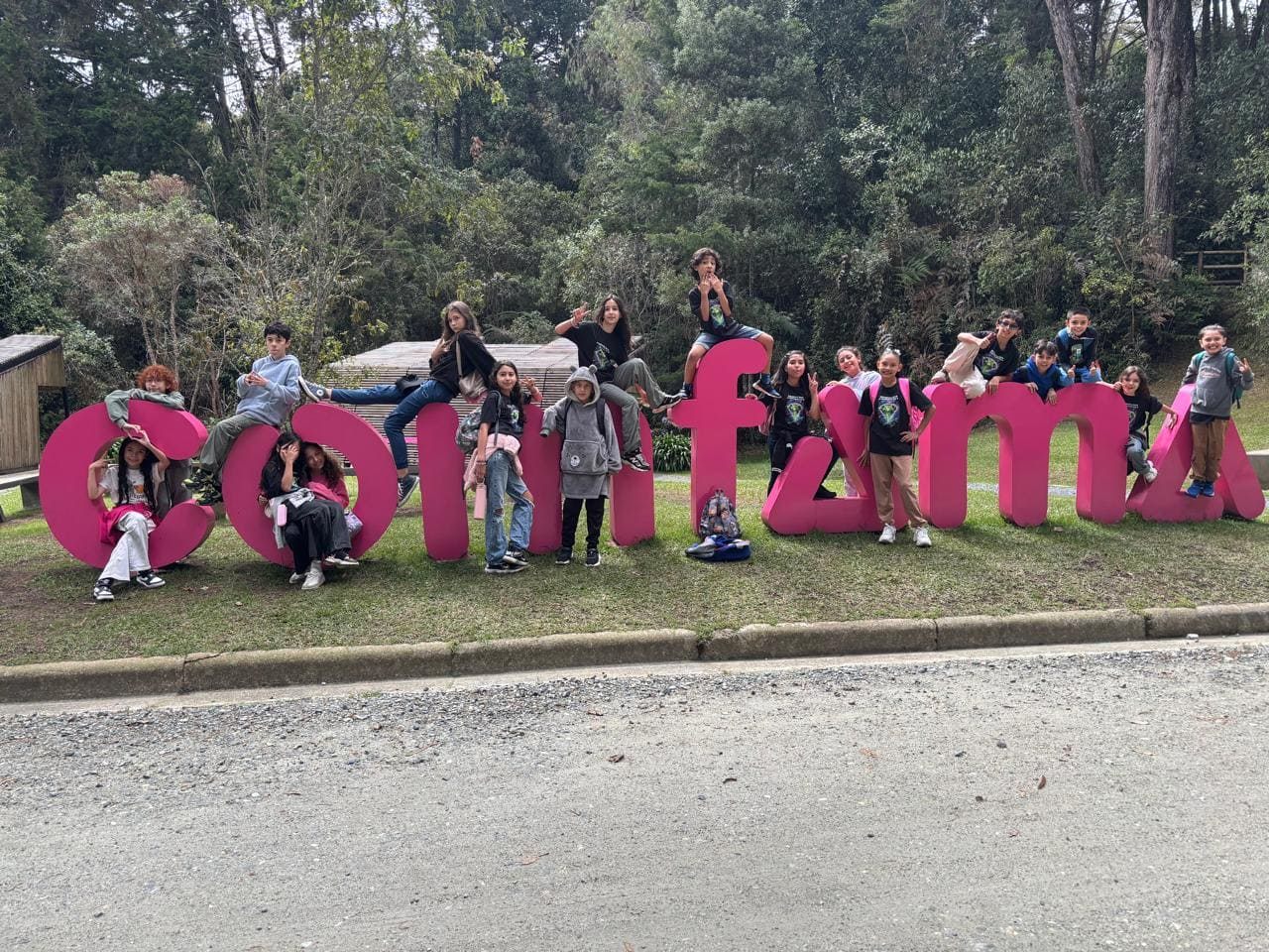 Estudiantes de Cosmo posando sobre las letras gigantes de Comfama en un parque