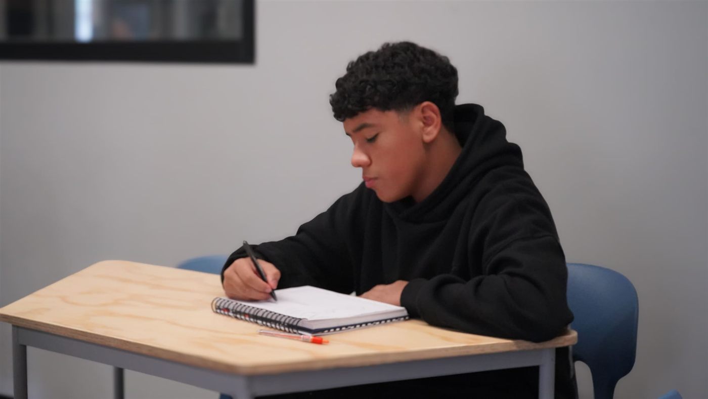 Estudiante escribiendo en su cuaderno en un salón