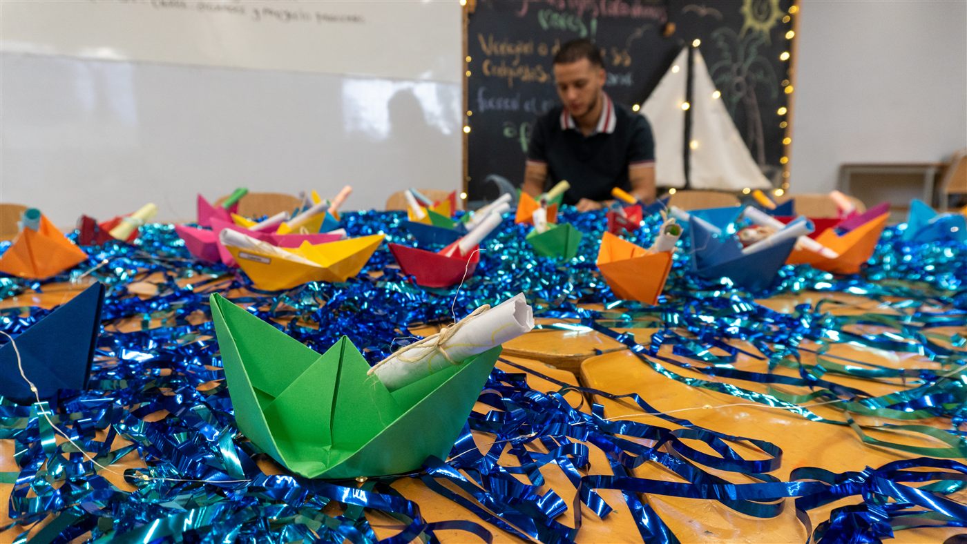 Barcos de papel de colores sobre una mesa decorada en un salón de clase