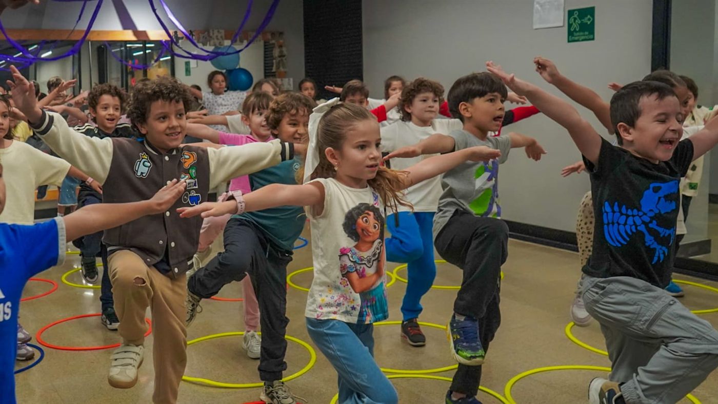 Niñas y niños bailan en una actividad del colegio, cada uno con su propia ropa